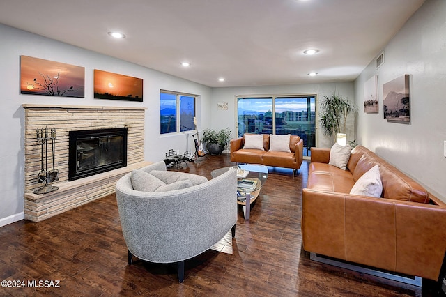 living room with a stone fireplace and dark hardwood / wood-style flooring