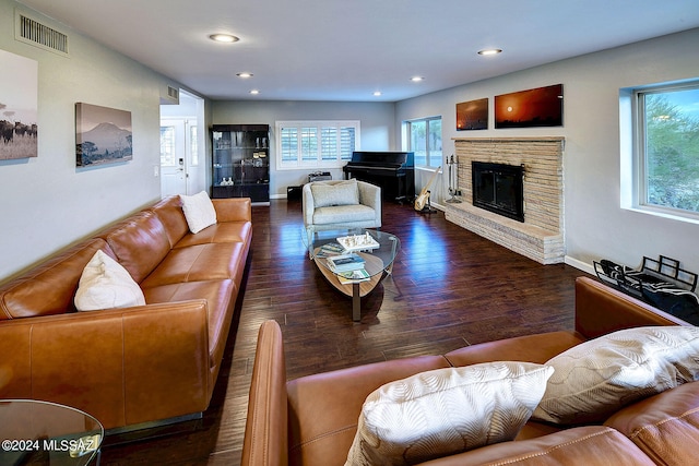 living room featuring a healthy amount of sunlight, a brick fireplace, and dark hardwood / wood-style floors