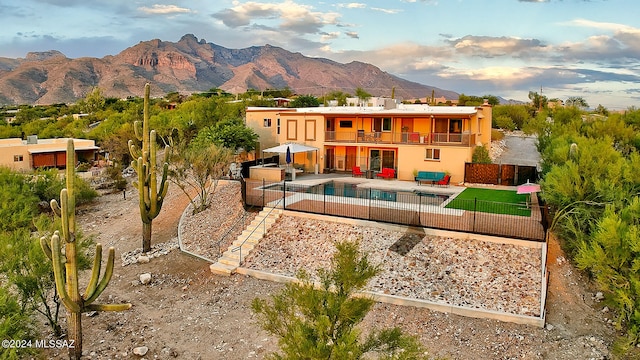 back of property with a balcony, an outdoor living space, a mountain view, and a patio area