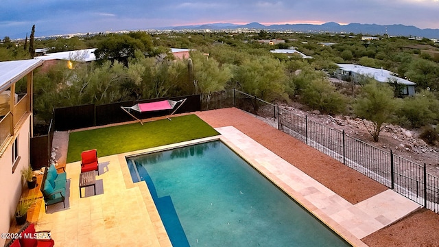 pool at dusk with a mountain view and a patio