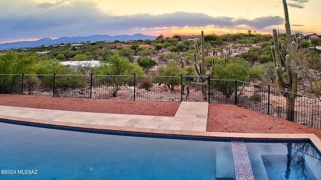 pool at dusk featuring a mountain view