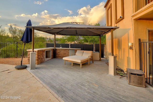 patio terrace at dusk featuring a gazebo and a deck