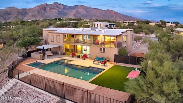 back of house featuring an outdoor hangout area, a patio, a swimming pool with hot tub, a mountain view, and a balcony