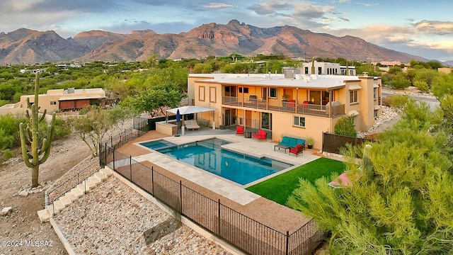 back of house featuring a patio, a mountain view, a fenced in pool, and a balcony