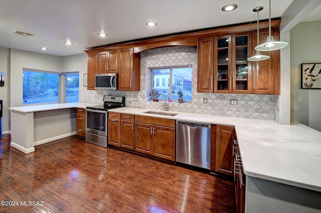 kitchen with decorative backsplash, hanging light fixtures, sink, appliances with stainless steel finishes, and dark hardwood / wood-style flooring