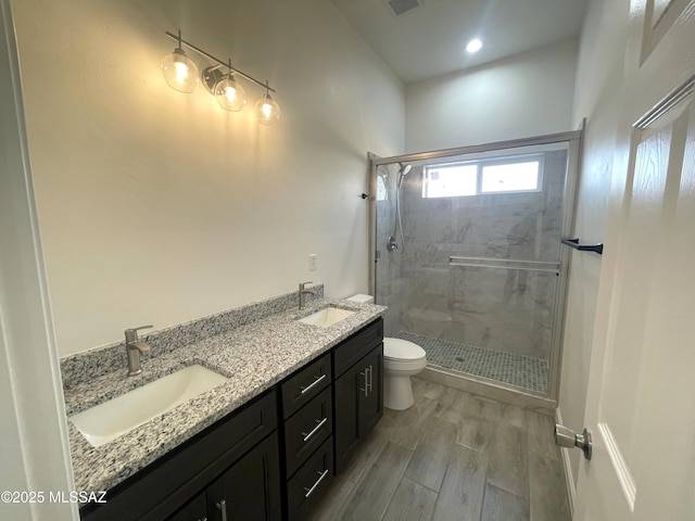bathroom featuring toilet, vanity, walk in shower, and hardwood / wood-style floors