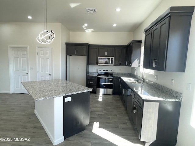 kitchen featuring a center island, dark hardwood / wood-style flooring, light stone countertops, sink, and appliances with stainless steel finishes