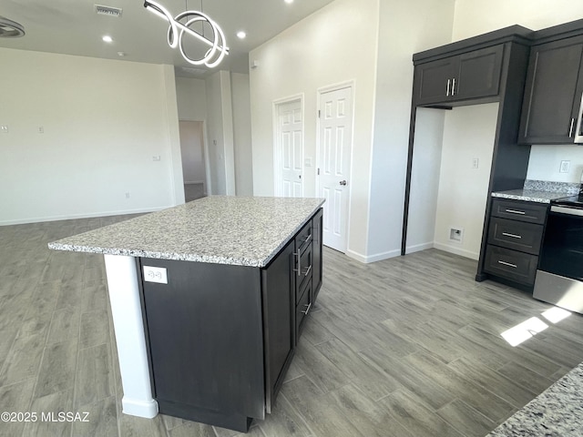 kitchen featuring electric stove, light wood-type flooring, a center island, and decorative light fixtures
