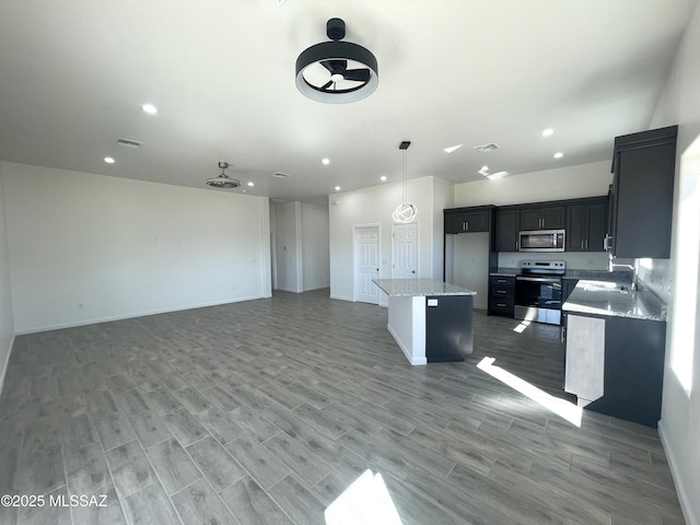 kitchen featuring appliances with stainless steel finishes, wood-type flooring, a kitchen island, and pendant lighting
