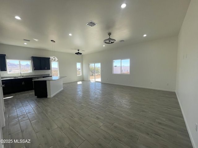kitchen with a wealth of natural light, pendant lighting, a center island, and hardwood / wood-style flooring