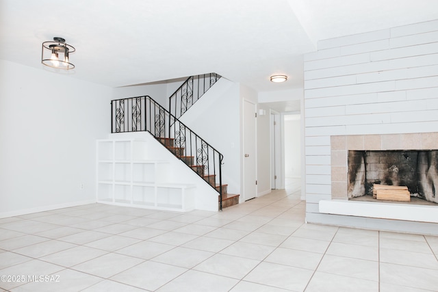 unfurnished living room featuring a tile fireplace and light tile patterned floors