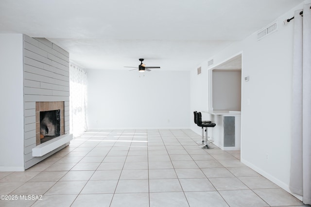 unfurnished living room featuring a fireplace, light tile patterned floors, and ceiling fan