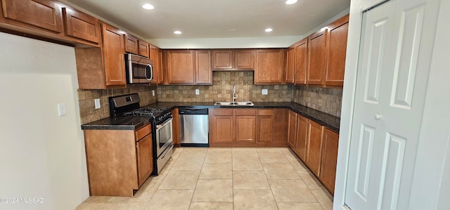 kitchen featuring appliances with stainless steel finishes, decorative backsplash, sink, and light tile patterned floors