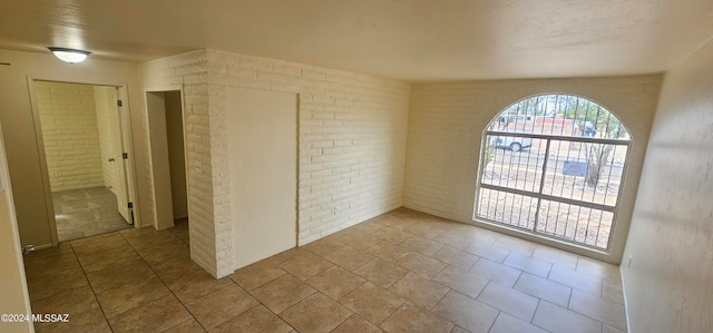 unfurnished room featuring brick wall