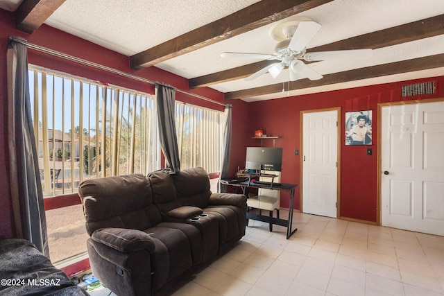 living room with ceiling fan, beamed ceiling, light tile patterned floors, and a textured ceiling