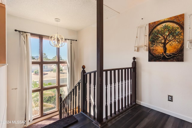 stairs featuring a textured ceiling, a chandelier, and hardwood / wood-style flooring