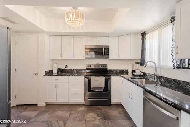 kitchen with appliances with stainless steel finishes, sink, dark stone counters, and white cabinetry