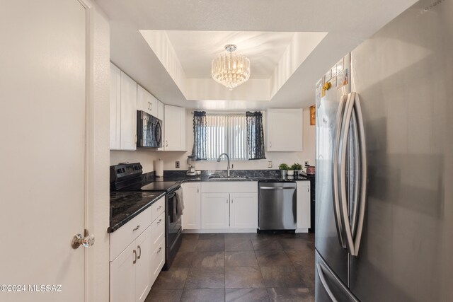 kitchen featuring sink, white cabinetry, hanging light fixtures, stainless steel appliances, and a raised ceiling