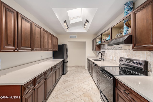 kitchen with appliances with stainless steel finishes, wall chimney exhaust hood, light tile patterned floors, a skylight, and sink