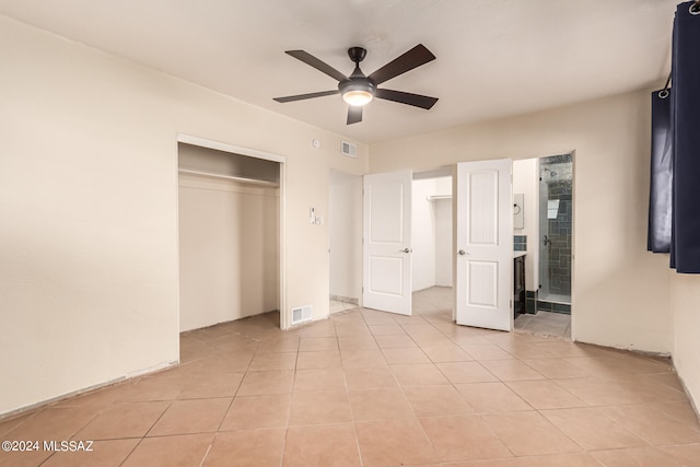 unfurnished bedroom with light tile patterned floors, ceiling fan, and a closet