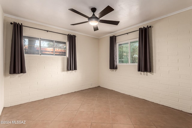 empty room with crown molding, light tile patterned floors, ceiling fan, and brick wall