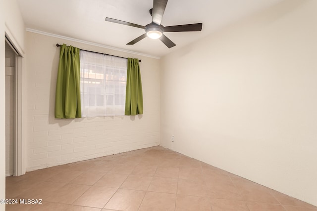 spare room featuring ceiling fan, light tile patterned floors, and crown molding