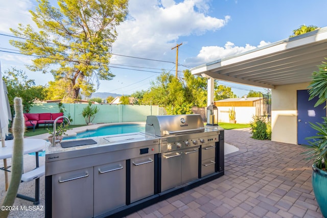 5731 E 2nd St, Tucson, AZ 85711 - view of patio with exterior kitchen, an outdoor structure, a sink, a fenced backyard, and a storage unit