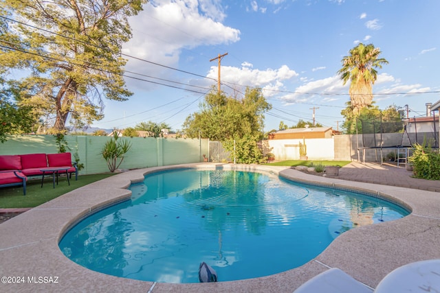 view of swimming pool with an outdoor hangout area, a trampoline, a storage unit, and a patio area