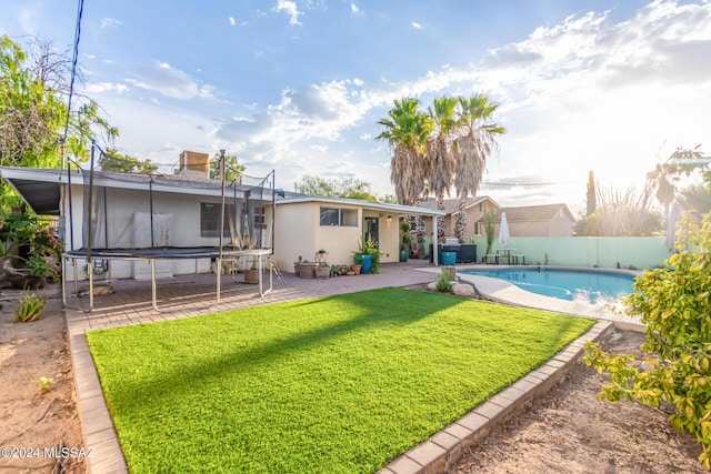 5731 E 2nd St, Tucson, AZ 85711 - rear view of house featuring a trampoline, a lawn, a fenced backyard, a patio area, and a fenced in pool