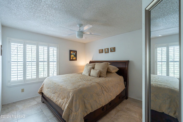 bedroom featuring light tile patterned flooring, multiple windows, ceiling fan, and a textured ceiling