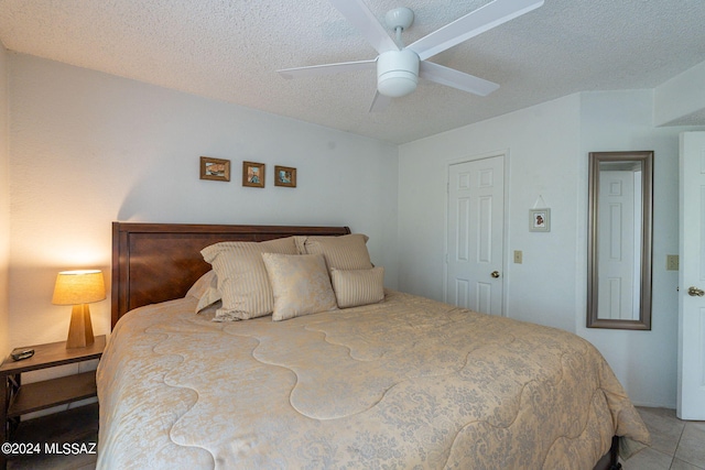 tiled bedroom with ceiling fan and a textured ceiling