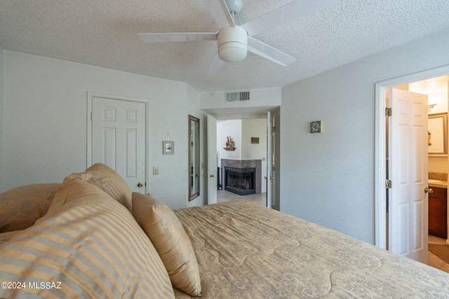 bedroom featuring ceiling fan, a textured ceiling, and connected bathroom