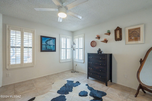 living area with a textured ceiling and ceiling fan