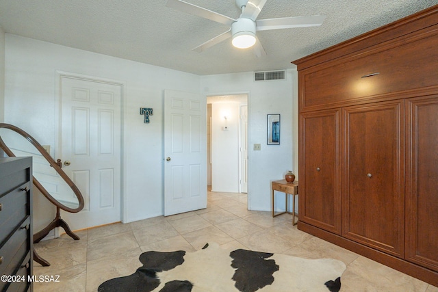 tiled bedroom featuring ceiling fan and a textured ceiling