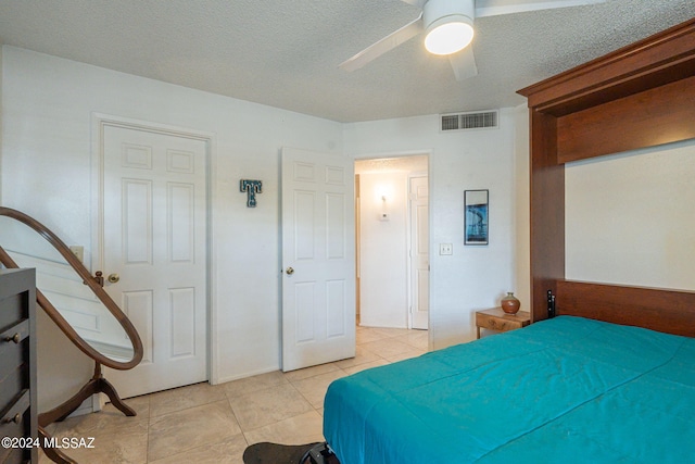 tiled bedroom with a textured ceiling and ceiling fan