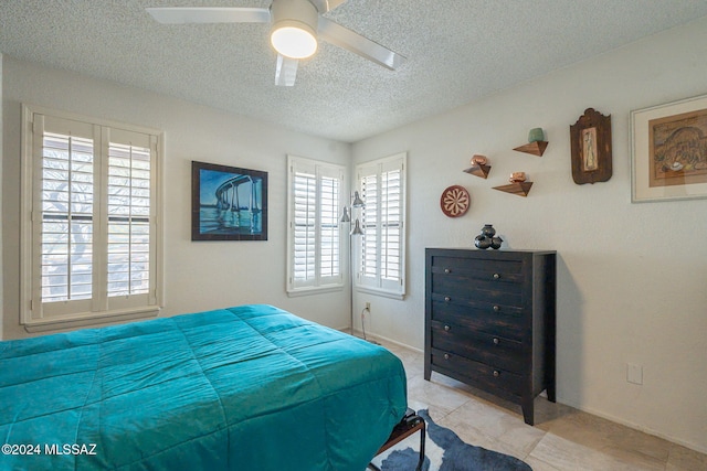 tiled bedroom featuring ceiling fan and a textured ceiling