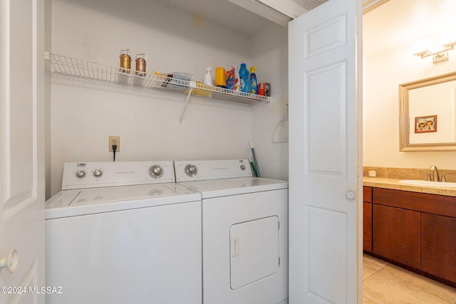 laundry room featuring washing machine and dryer, sink, and light tile patterned floors