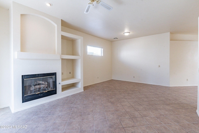 unfurnished living room featuring light tile patterned flooring, a large fireplace, built in features, and ceiling fan