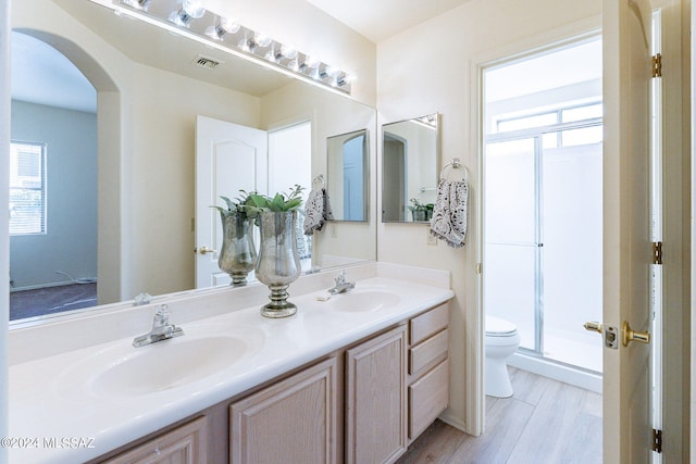 bathroom with a shower with door, vanity, wood-type flooring, and toilet