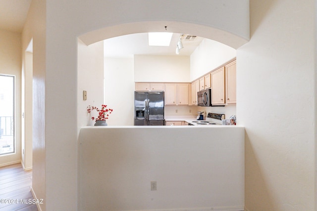 kitchen with light brown cabinets, white range with electric stovetop, rail lighting, black fridge with ice dispenser, and light hardwood / wood-style floors