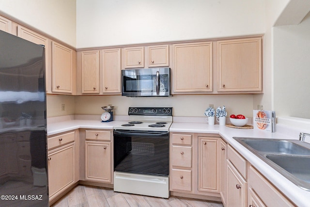 kitchen with light brown cabinetry, light wood-type flooring, and white range with electric cooktop