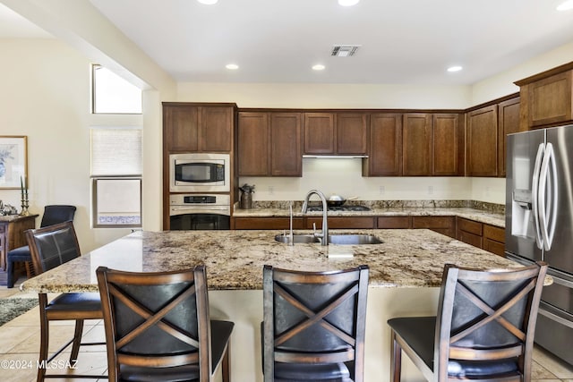 kitchen with a kitchen island with sink, a breakfast bar, and appliances with stainless steel finishes