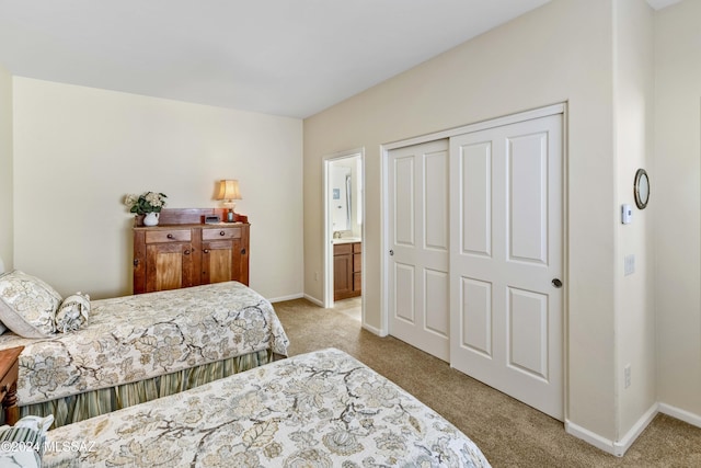 carpeted bedroom with ensuite bathroom and a closet