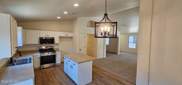 kitchen with vaulted ceiling, a center island, stainless steel appliances, and white cabinetry