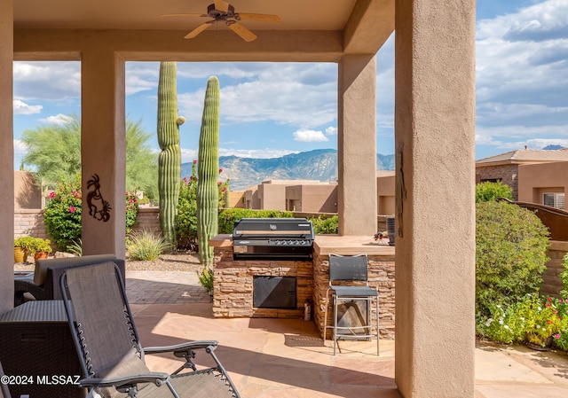 view of patio with ceiling fan, area for grilling, and a mountain view