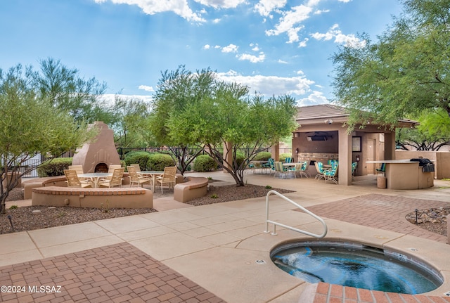 view of pool featuring an outdoor fireplace, an in ground hot tub, and a patio