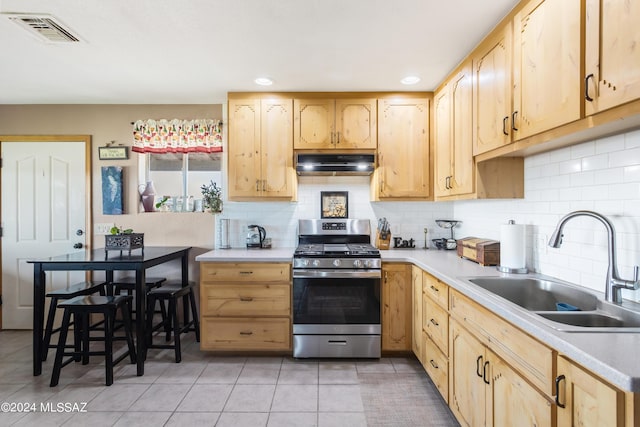 kitchen featuring light brown cabinetry, stainless steel range with gas cooktop, sink, and decorative backsplash