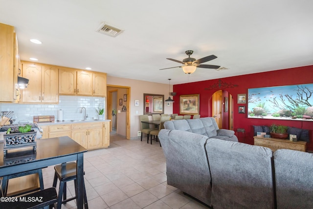 living room featuring light tile patterned flooring, ceiling fan, and sink