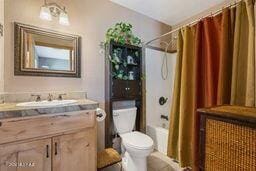 full bathroom with shower / bath combination with curtain, vanity, and toilet