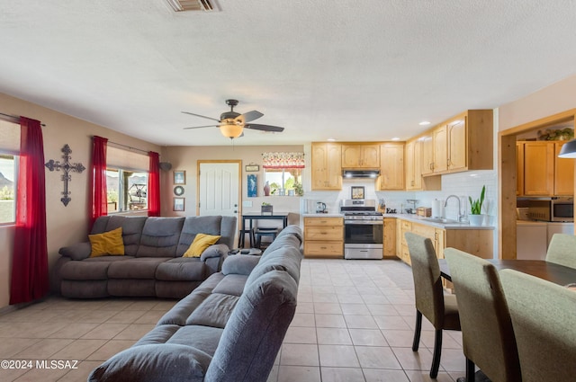 living room with ceiling fan, sink, and light tile patterned floors